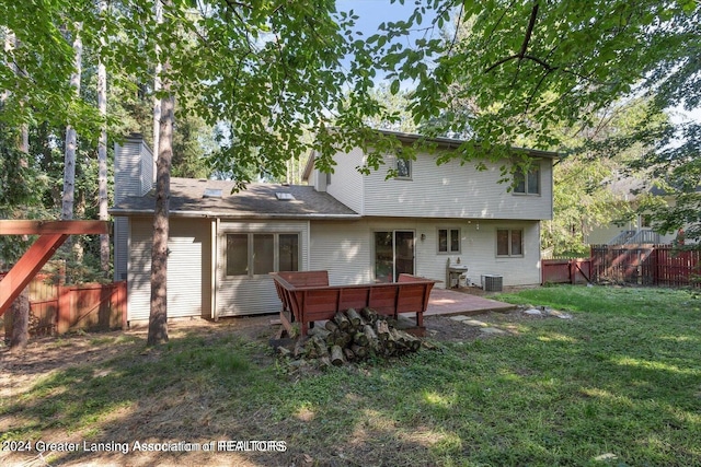 rear view of property featuring a lawn, central AC unit, and a patio area