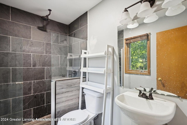 bathroom featuring a tile shower, sink, and toilet