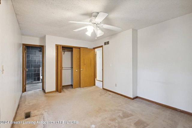 unfurnished bedroom with a closet, a textured ceiling, light colored carpet, and ceiling fan