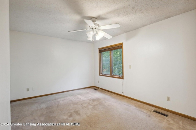 carpeted spare room featuring a textured ceiling and ceiling fan