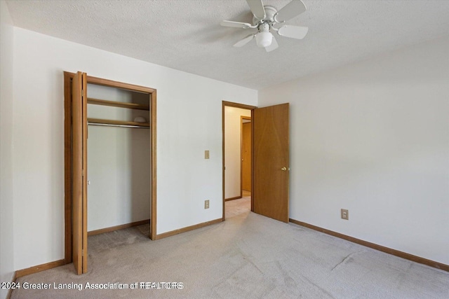 unfurnished bedroom with ceiling fan, a textured ceiling, a closet, and light carpet