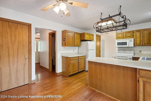 kitchen featuring ceiling fan, kitchen peninsula, white appliances, a textured ceiling, and light hardwood / wood-style floors