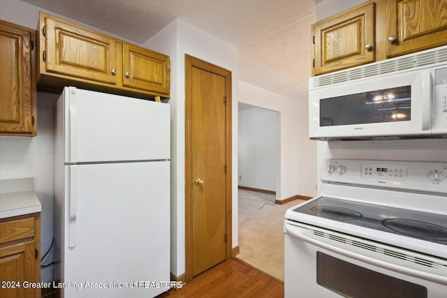 kitchen with light hardwood / wood-style flooring and white appliances