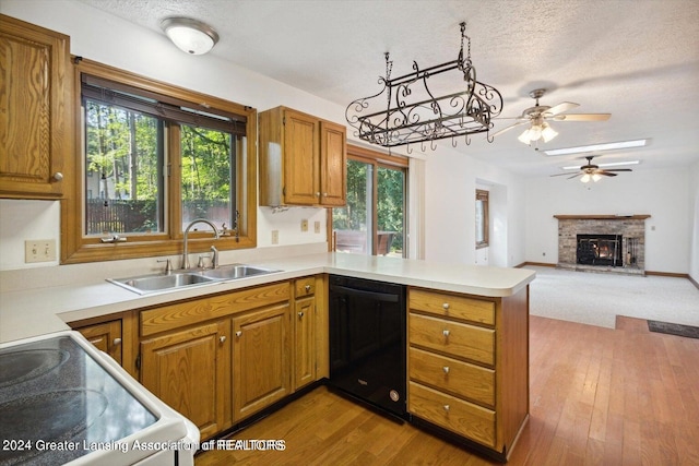 kitchen with kitchen peninsula, a fireplace, dishwasher, ceiling fan, and sink