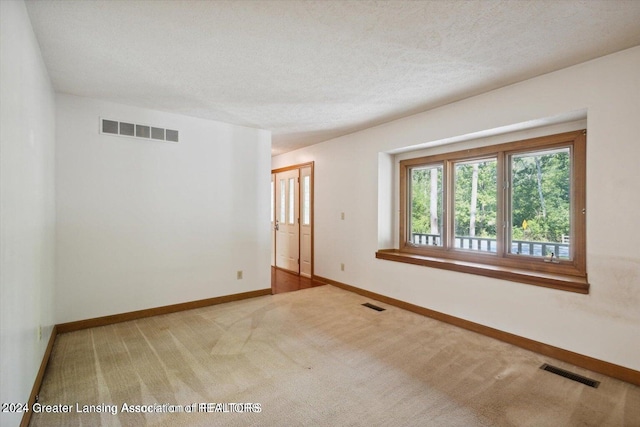 empty room with carpet floors and a textured ceiling