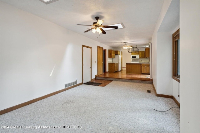 spare room featuring ceiling fan, light colored carpet, a textured ceiling, and a skylight