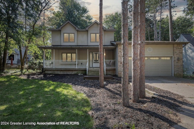 view of front of property with a yard, a garage, and a porch