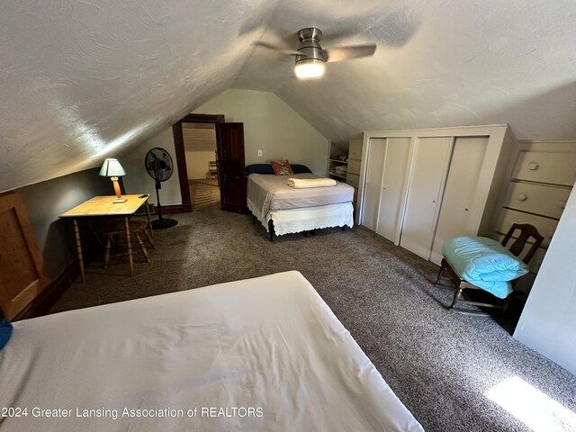 bedroom featuring a closet, a textured ceiling, lofted ceiling, dark colored carpet, and ceiling fan