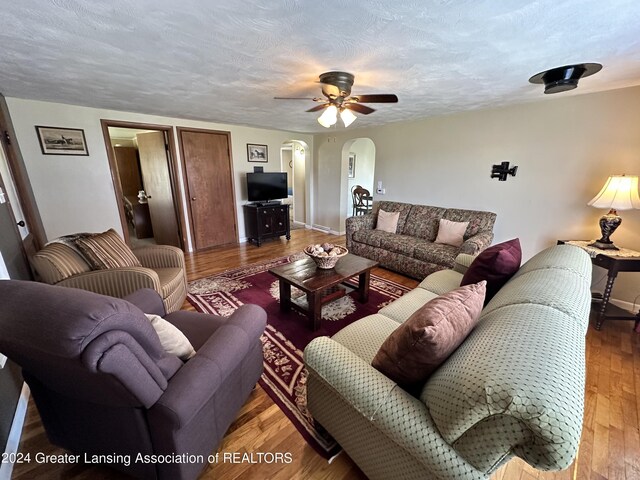 living room with ceiling fan, hardwood / wood-style flooring, and a textured ceiling