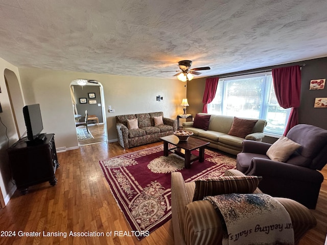 living room with wood-type flooring, ceiling fan, and a textured ceiling