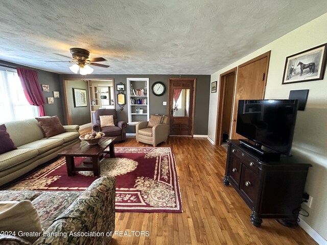 living room with ceiling fan, a textured ceiling, and light hardwood / wood-style flooring