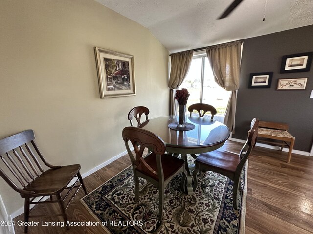 dining space with a textured ceiling, dark hardwood / wood-style floors, and vaulted ceiling