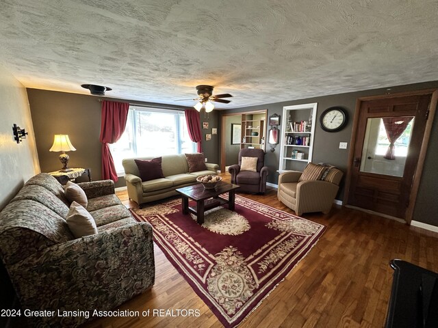 living room featuring ceiling fan, a textured ceiling, and hardwood / wood-style flooring