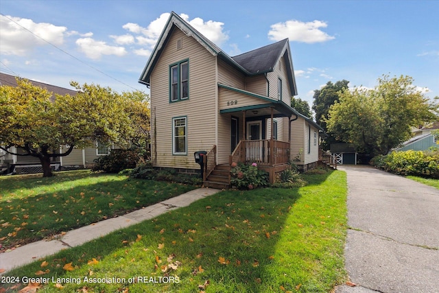 view of property featuring covered porch and a front yard