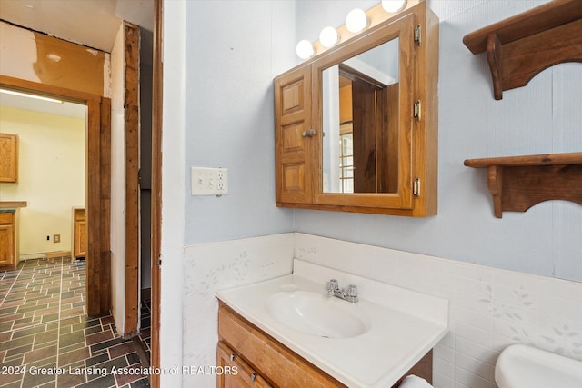 bathroom with tile walls, vanity, and toilet