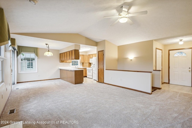 kitchen with ceiling fan, kitchen peninsula, decorative light fixtures, light colored carpet, and vaulted ceiling