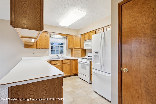 kitchen featuring a textured ceiling, white appliances, kitchen peninsula, and sink