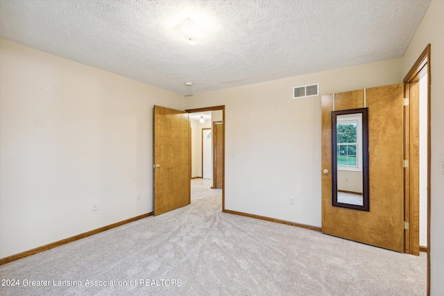 unfurnished bedroom featuring a textured ceiling and light carpet