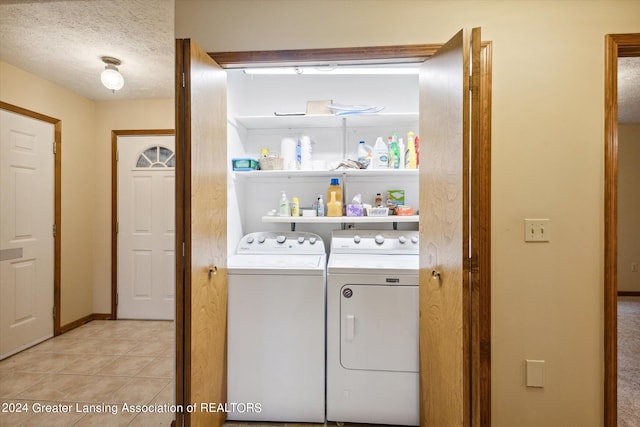 washroom featuring a textured ceiling, light tile patterned flooring, and washer and clothes dryer