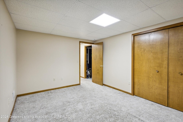 unfurnished bedroom featuring a drop ceiling, carpet, and a closet