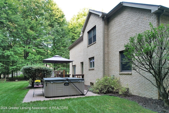 rear view of house featuring a gazebo, a hot tub, and a lawn