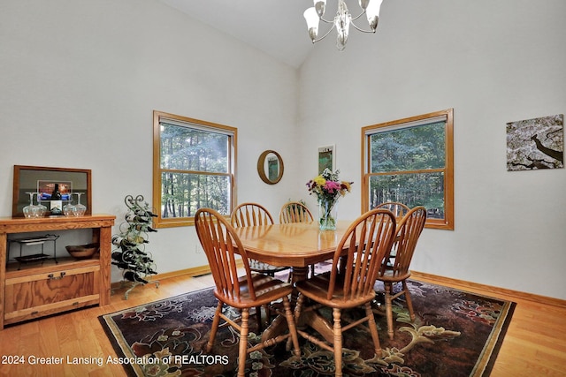 dining space with a chandelier, plenty of natural light, high vaulted ceiling, and wood-type flooring