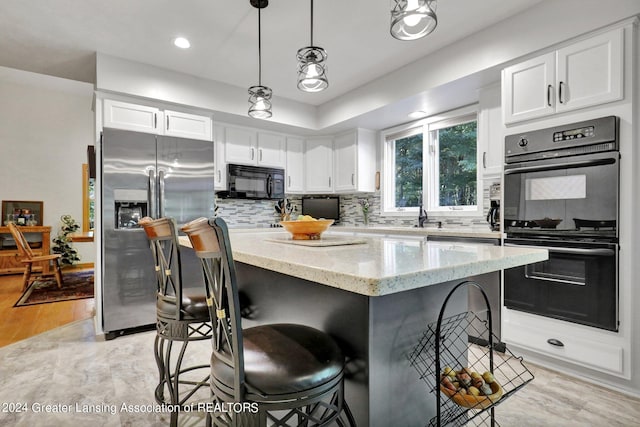 kitchen featuring backsplash, black appliances, pendant lighting, light hardwood / wood-style floors, and white cabinetry