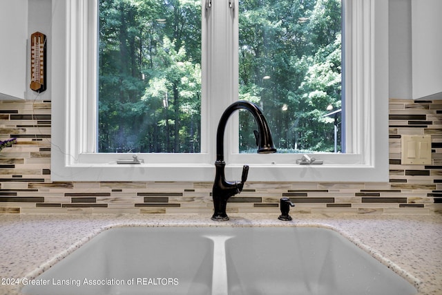 interior details featuring decorative backsplash, light stone counters, and sink