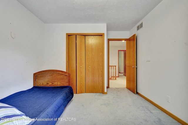 carpeted bedroom with a textured ceiling and a closet