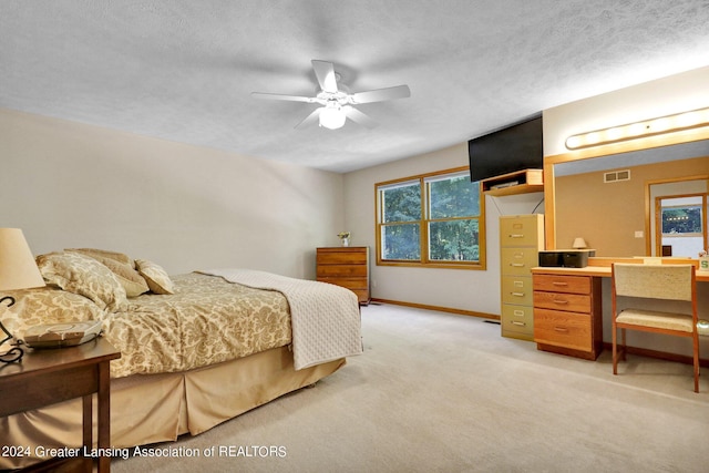 bedroom featuring ceiling fan, light colored carpet, and a textured ceiling