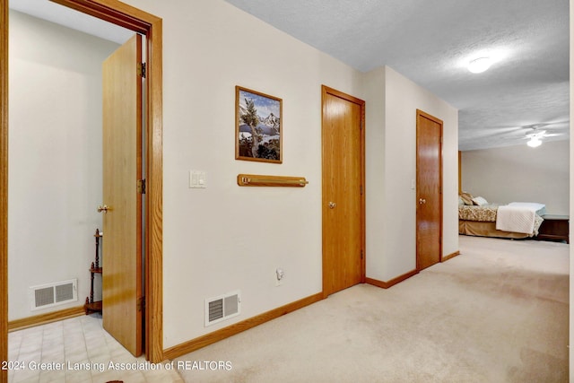 corridor with light carpet and a textured ceiling