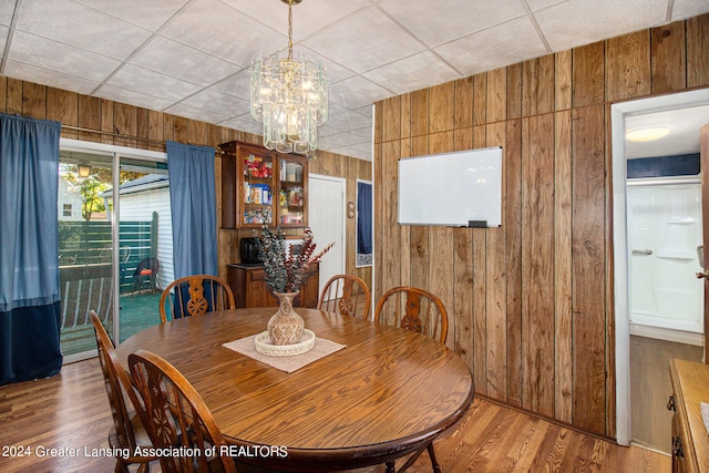 dining space featuring wooden walls, hardwood / wood-style floors, and a paneled ceiling