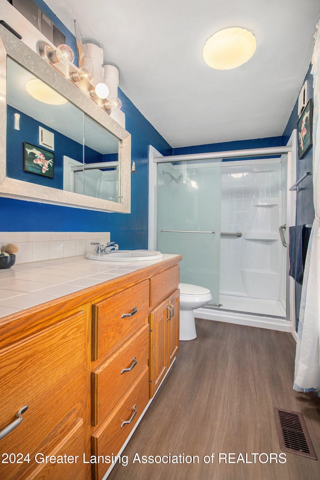 bathroom with wood-type flooring, an enclosed shower, vanity, and toilet