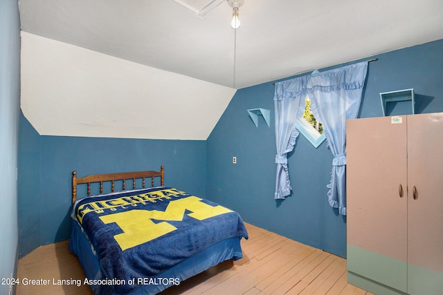 bedroom with wood-type flooring and vaulted ceiling