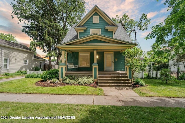 view of front of home with a porch and a lawn