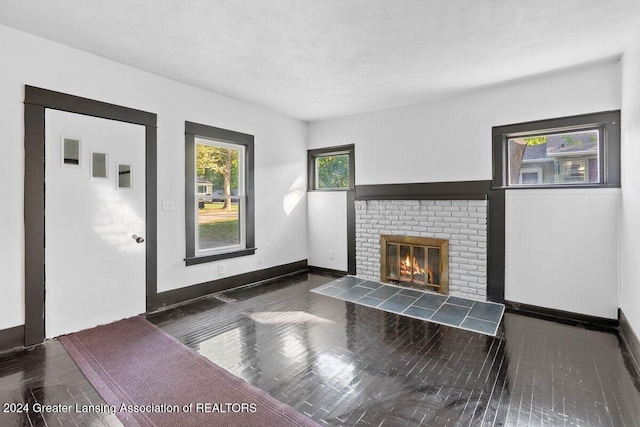 unfurnished living room featuring dark hardwood / wood-style floors and a brick fireplace