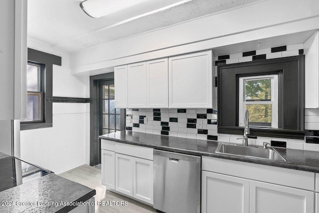 kitchen featuring sink, stainless steel dishwasher, decorative backsplash, light hardwood / wood-style floors, and white cabinetry