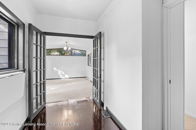 hallway featuring french doors, vaulted ceiling, crown molding, hardwood / wood-style flooring, and a chandelier