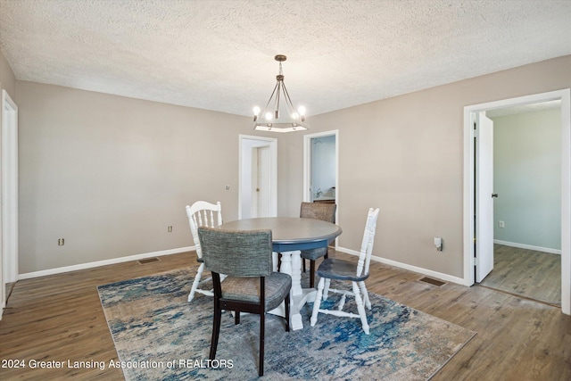 dining room featuring a notable chandelier, a textured ceiling, and dark wood-type flooring