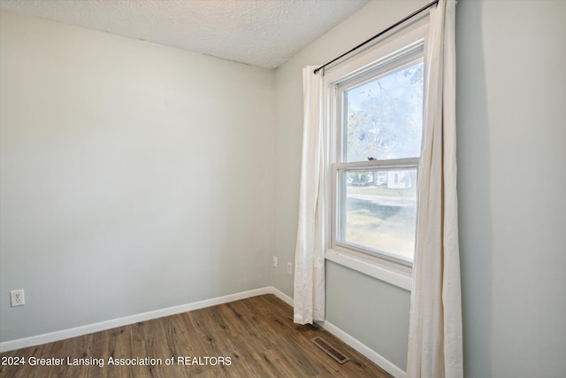 unfurnished room with a textured ceiling and hardwood / wood-style floors