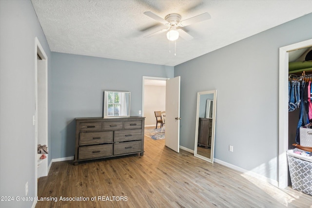 bedroom featuring light wood-type flooring, a textured ceiling, ceiling fan, and a closet