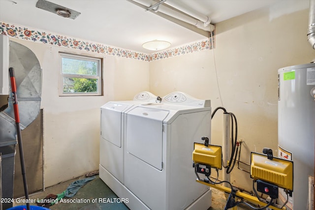 clothes washing area featuring water heater and washer and clothes dryer