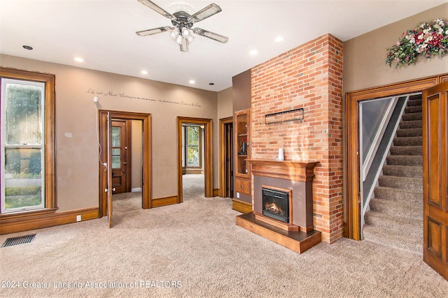 living room featuring a fireplace, light colored carpet, and ceiling fan