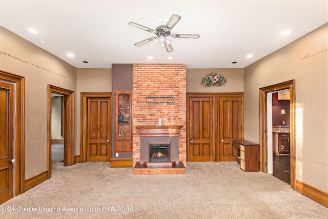 unfurnished living room with a fireplace, carpet floors, and ceiling fan