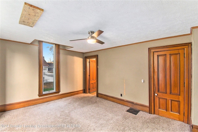 carpeted spare room with ceiling fan, crown molding, and a textured ceiling