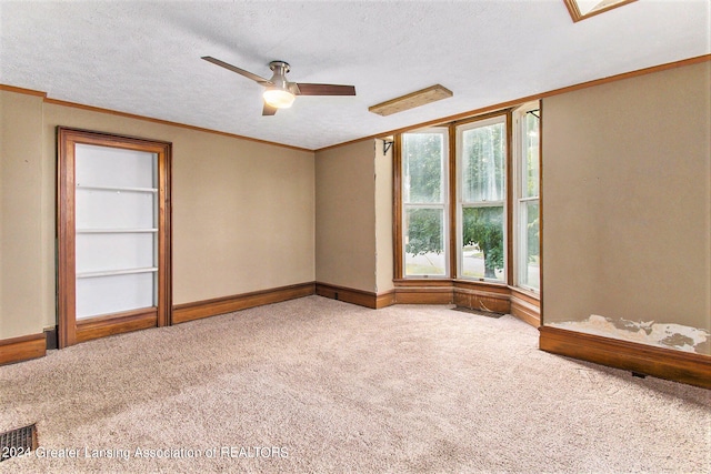 spare room with a skylight, a textured ceiling, ceiling fan, ornamental molding, and light colored carpet