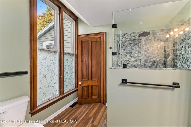 bathroom featuring toilet, a shower, and hardwood / wood-style floors