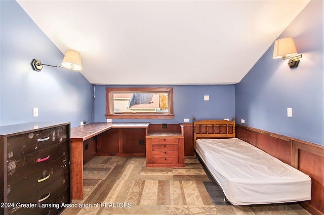 unfurnished bedroom featuring built in desk and vaulted ceiling