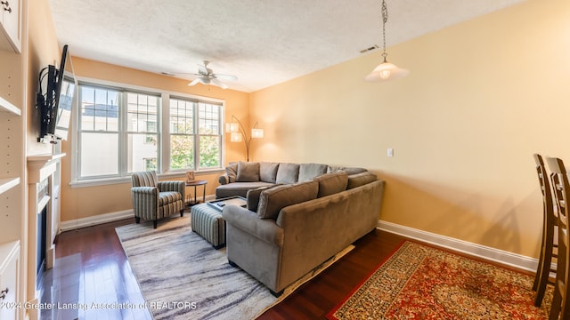 living room featuring a textured ceiling, dark hardwood / wood-style floors, and ceiling fan