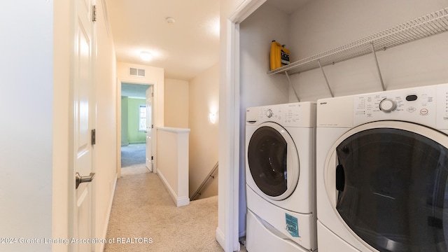 washroom with washing machine and clothes dryer and light colored carpet